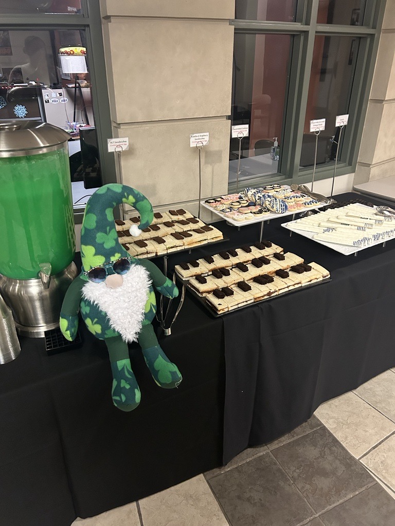 Jerome the gnome sat on a table displayed with green punch, sandwiches placed to look like a piano, sunglasses shaped cookies, and baseball bat painted pretzel rods