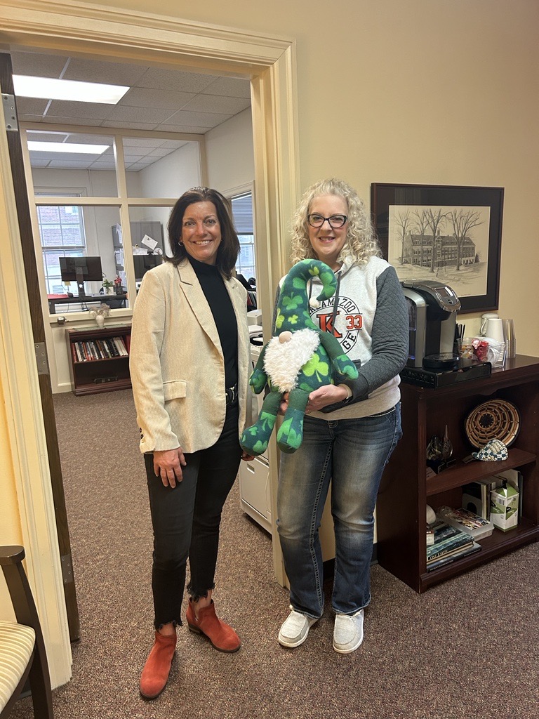 Image of Jerome the leprechaun gnome held by Administrative Secretary to the President & Provost, Wendy Fleckenstein, and Academic Support Specialist, Sarah Gillig